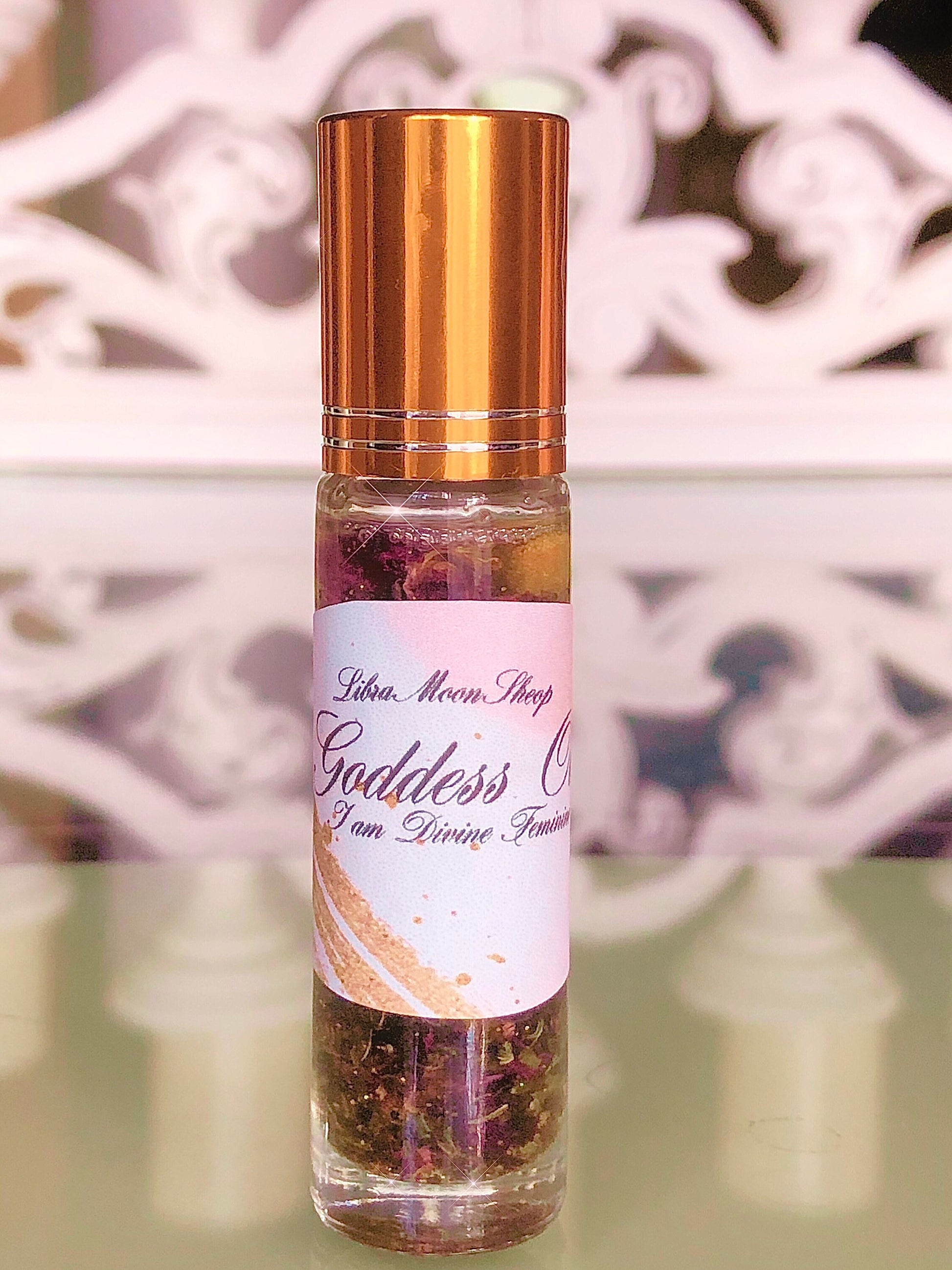 Roll-on bottle with gold cap and pink label on a white decorative background